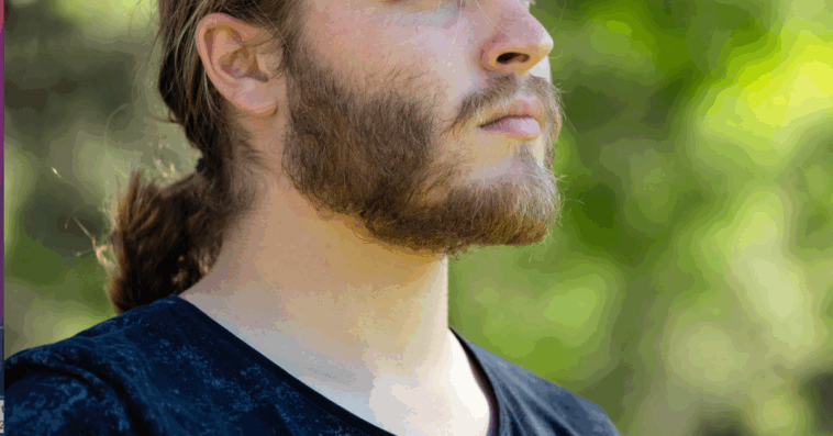 A man with a ponytail standing in profile.