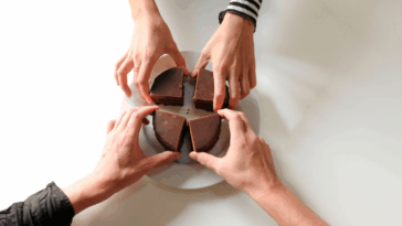 Four hands reaching for four pieces of choclolate.