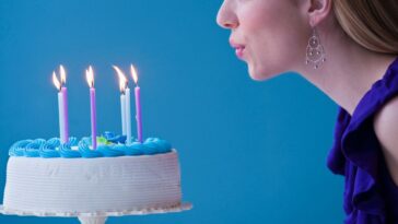 Young woman blowing candles on birthday cake.
