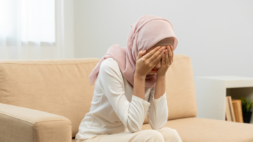 Muslim woman with her face in her hands