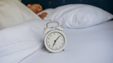 man in bed with alarm clock