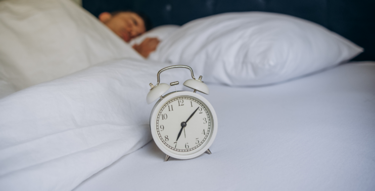 man in bed with alarm clock
