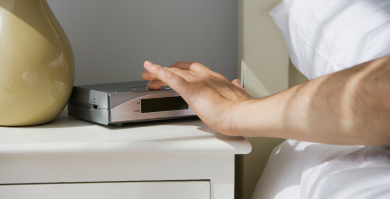 person turning off alarm clock