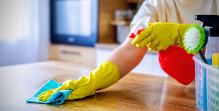 person with cleaning supplies wiping counter