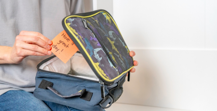 A person putting a note in a lunchbox.