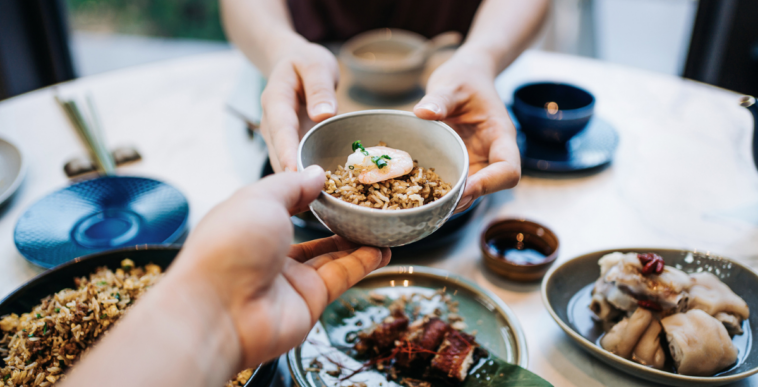 Two people sharing a number of small plates of food.