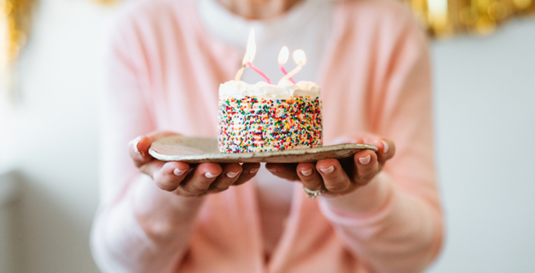 A woman holding a small birthday cake with a candle in it.
