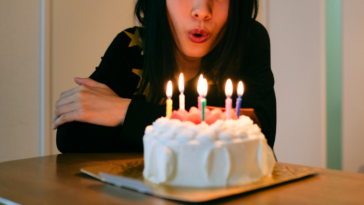 woman blowing out birthday candles on a white cake