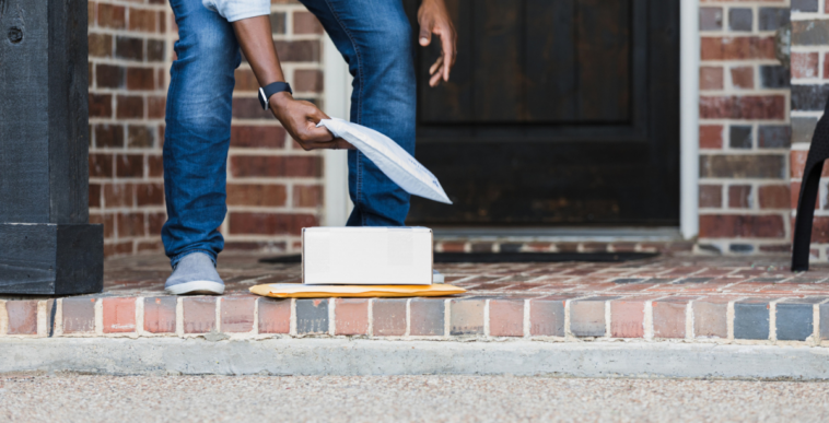 A man picking up packages on a doorstep.