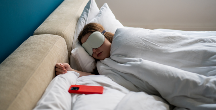 young woman sleeping with her cellphone next to her