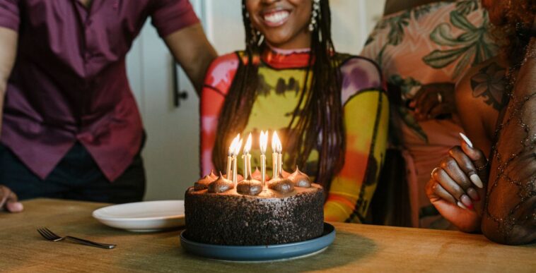 Woman smiling While Looking At Birthday Cake During Dinner Party.