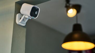 White cctv camera recording video, enhancing safety and protection in a modern interior space illuminated by warm lighting, creating a secure and inviting atmosphere.Modern wireless security camera monitoring a room.