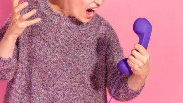 Photo of an arrogant, rude lady dressed in a pullover screaming into a retro phone, empty space isolated pink color background.