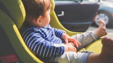 A baby girl 8 months old sitting in her car seat enjoying the warmth of the sun.