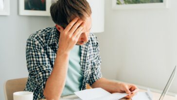 Pensive man thinking about high prices. Managing family finances. Rise of utilities, gas, electricity, rental charges, water bill due to inflation and global crisis. Facing downturn including energy. Planning family budget while sitting in kitchen.
