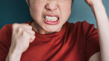 A woman with a clenched jaw holding her fists in the air.
