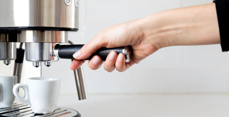 A woman using an espresso machine.