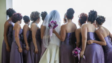 A bride surrounded by Bridesmaids in purple dresses.