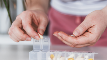 A person organizing pills into a daily pill box.