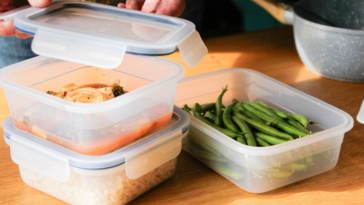Someone assembling tupperware containers full of leftovers.