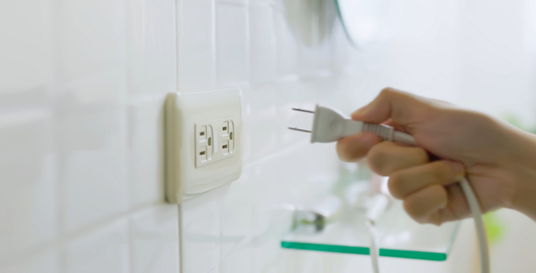 A hand unplugging a plug from a socket.