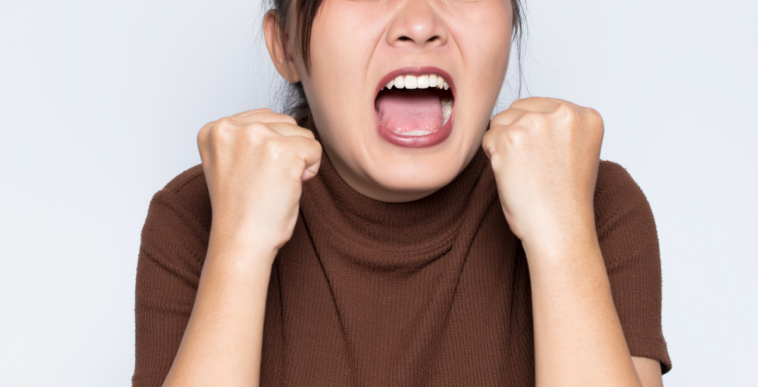 A woman clenching her fists and screaming.