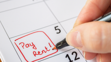 Someone writing "pay rent" on a calendar.