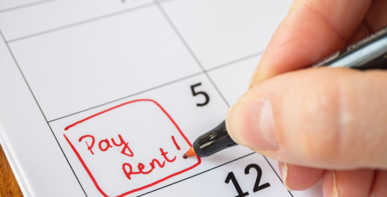 Someone writing "pay rent" on a calendar.