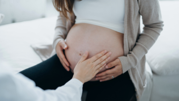 A man touching a woman's pregnant belly.