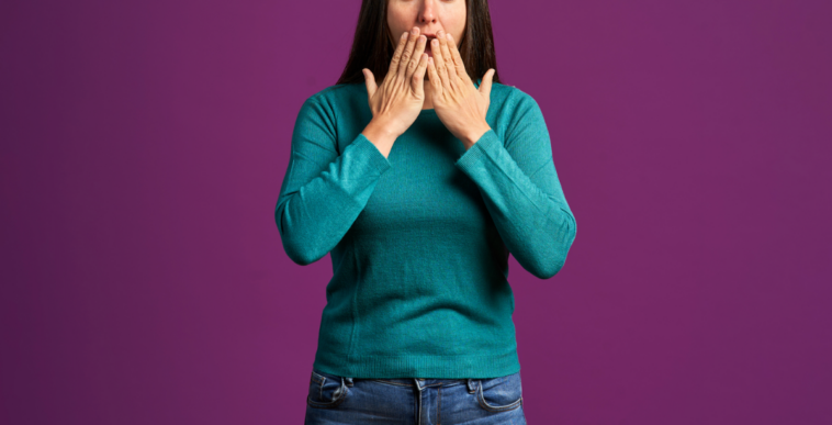 A woman holding her hands in front of her mouth.