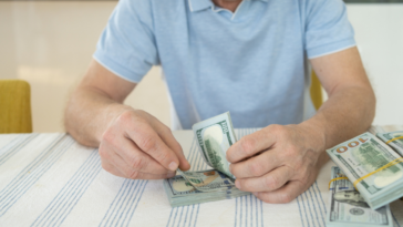A man sitting at a table counting money.
