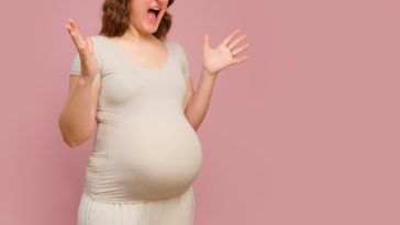 A pregnant woman emphatically holding out her arms and screaming.