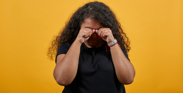 A woman covering her face and crying.