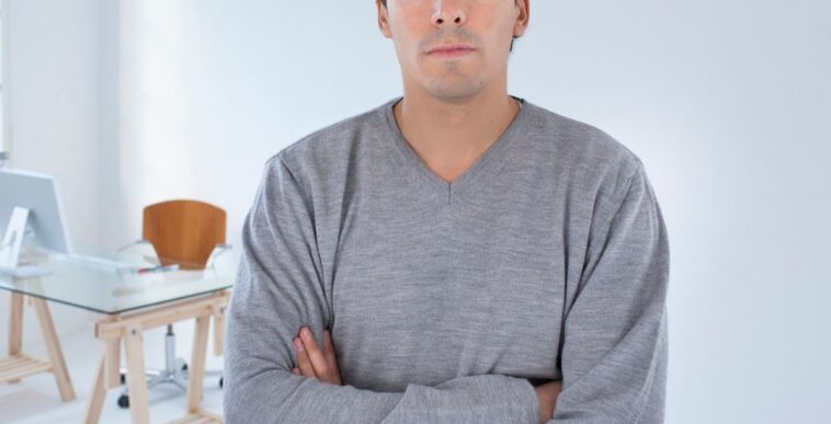 Man standing in an office arms crossed.