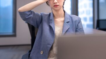 Stressed young businesswoman in the office, holding her hand to her head.