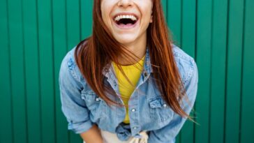 Young, beautiful red hair woman laughing at the camera - Portrait green background.