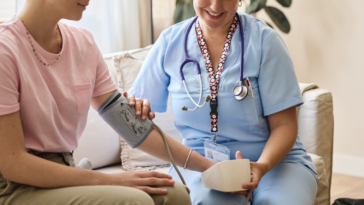 A nurse sitting next to a woman with a chemo IV in her arm.