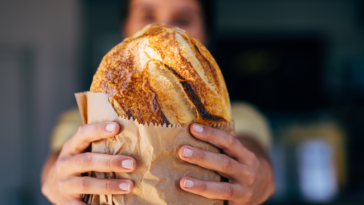 woman holding bread wrapped in brown paper