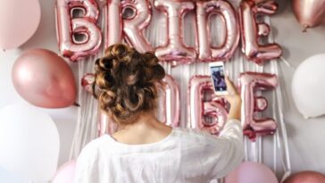 woman in white takes selfie in front of bridal shower decorations