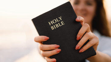 young woman holding out Bible