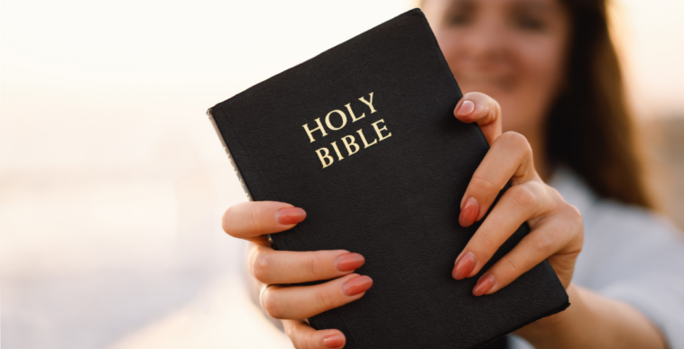 young woman holding out Bible