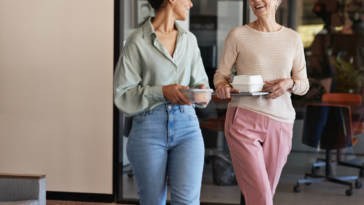 Two women walking and holding coffee cups.