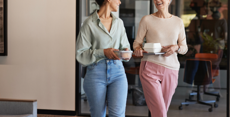 Two women walking and holding coffee cups.