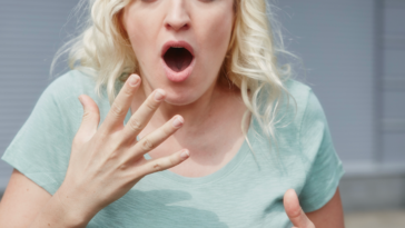 A woman with her mouth open holding her hand close to her mouth.