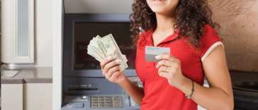 A young girl holding cash in one hand and a credit card in another.