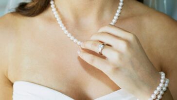 Close-up of a bride touching her pearl necklace.