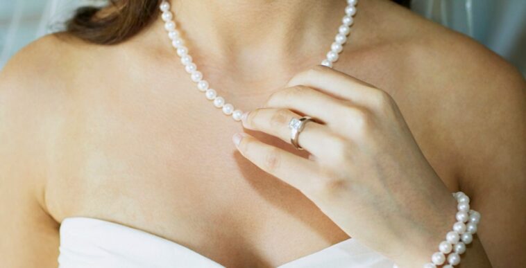 Close-up of a bride touching her pearl necklace.